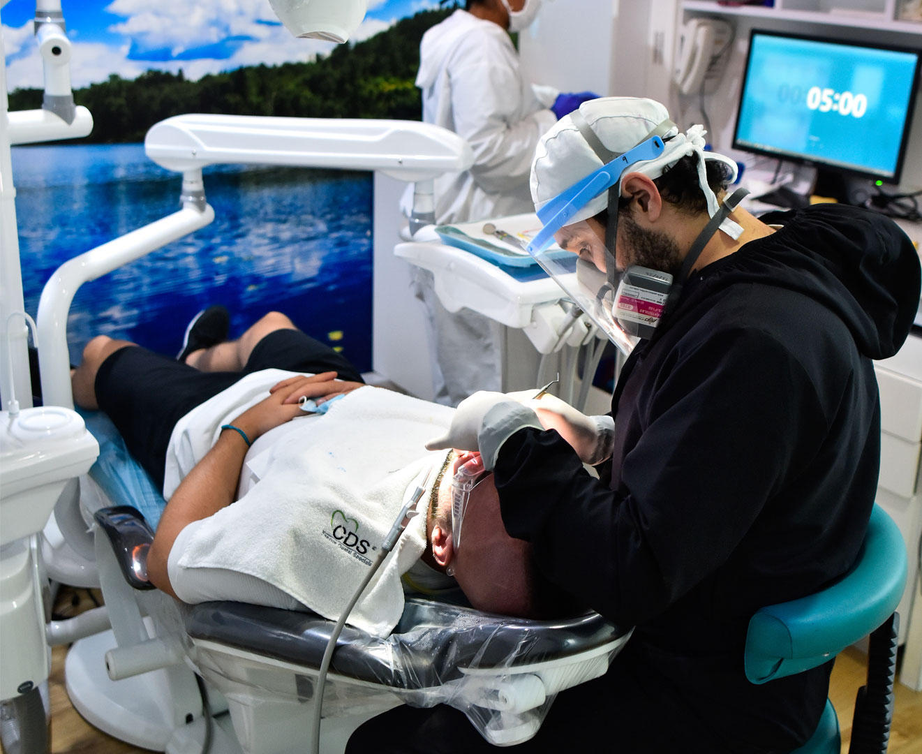 Imagen de dentista y asistente dental trabajando juntos en consultorio, aplicando protocolos de limpieza y atención profesional