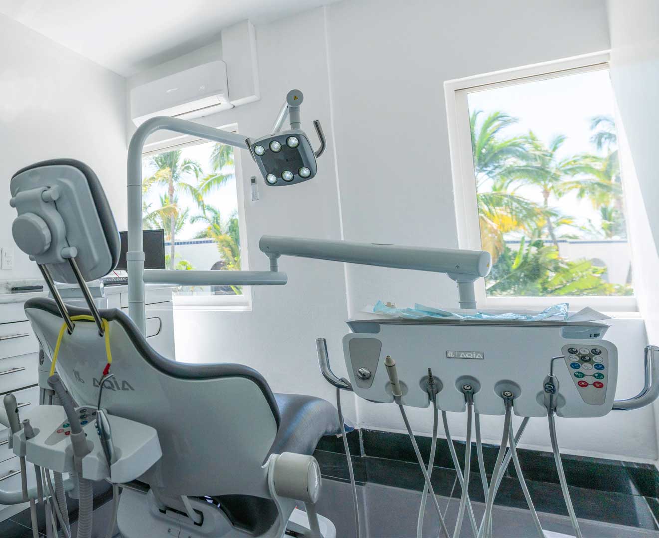 Silla de dentista totalmente equipada con instrumental, ubicada en clínica con vista a palmeras