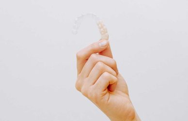 Imagen de una mano mostrando alineadores Invisalign, tecnología avanzada en ortodoncia invisible