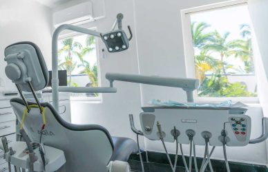 Silla de dentista totalmente equipada con instrumental, ubicada en clínica con vista a palmeras